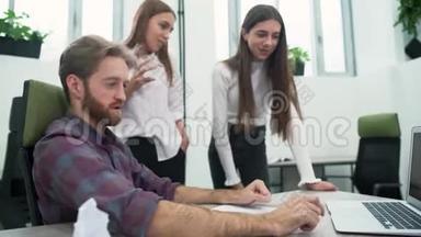 一个留胡子的家伙和两个年轻的女孩正在办公室里讨论<strong>工作计划</strong>。 高级经理展示
